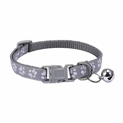 Gray adjustable nylon cat collar with bell and pink collar on a cat, featuring soft paw print design in various colors.