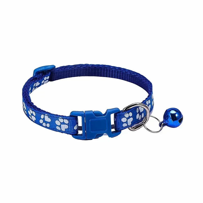 Navy blue adjustable nylon cat collar with bell and paw print design, worn by a cat with a pink collar, displayed among various colors.